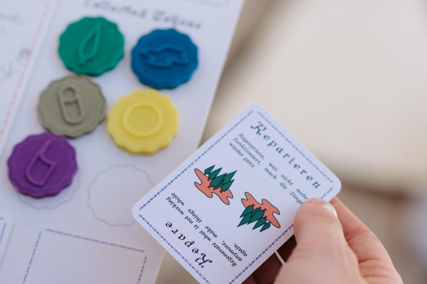 Das Bild Zeit eine Person die die ein Notizbogen in der Hand hält mit bunten Spielsteinen.
